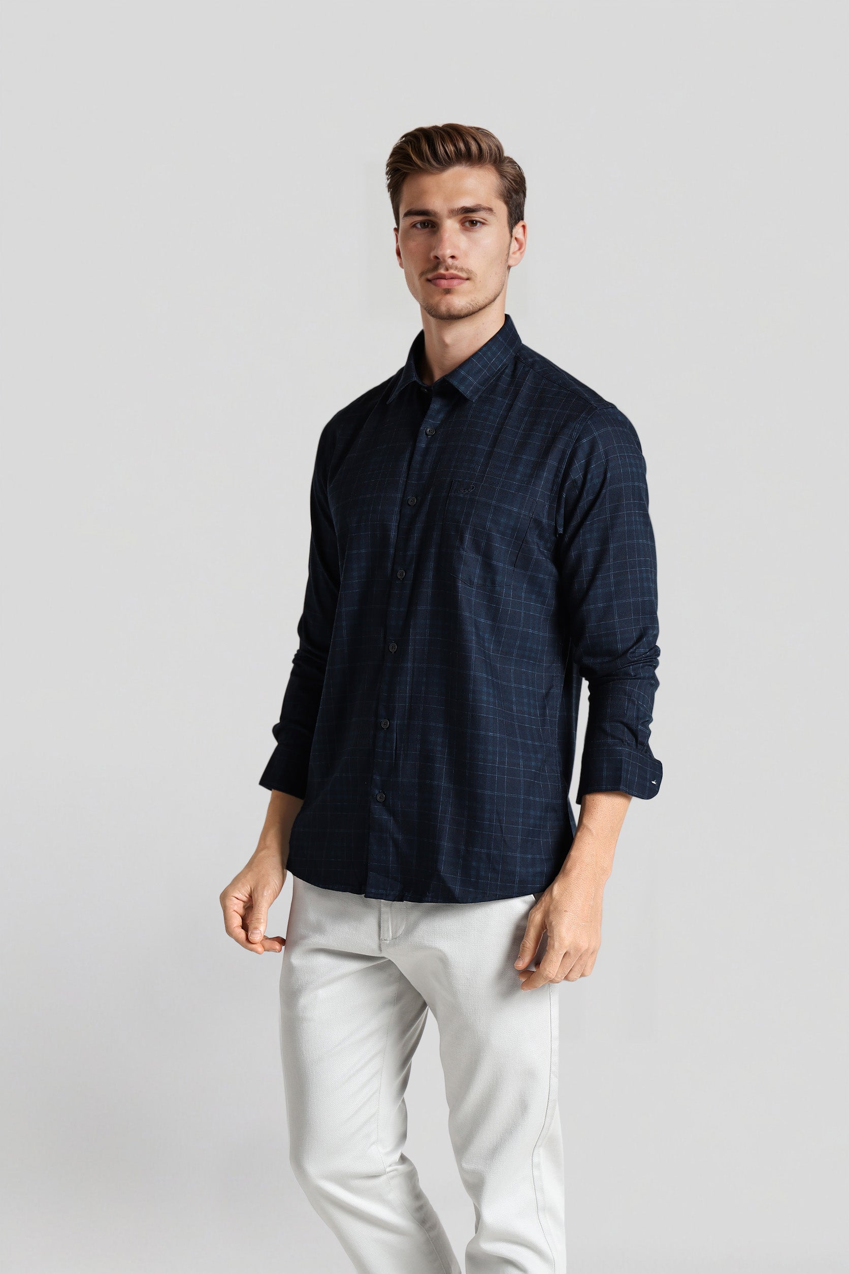 Man wearing a dark blue shirt and light-colored pants on a plain background