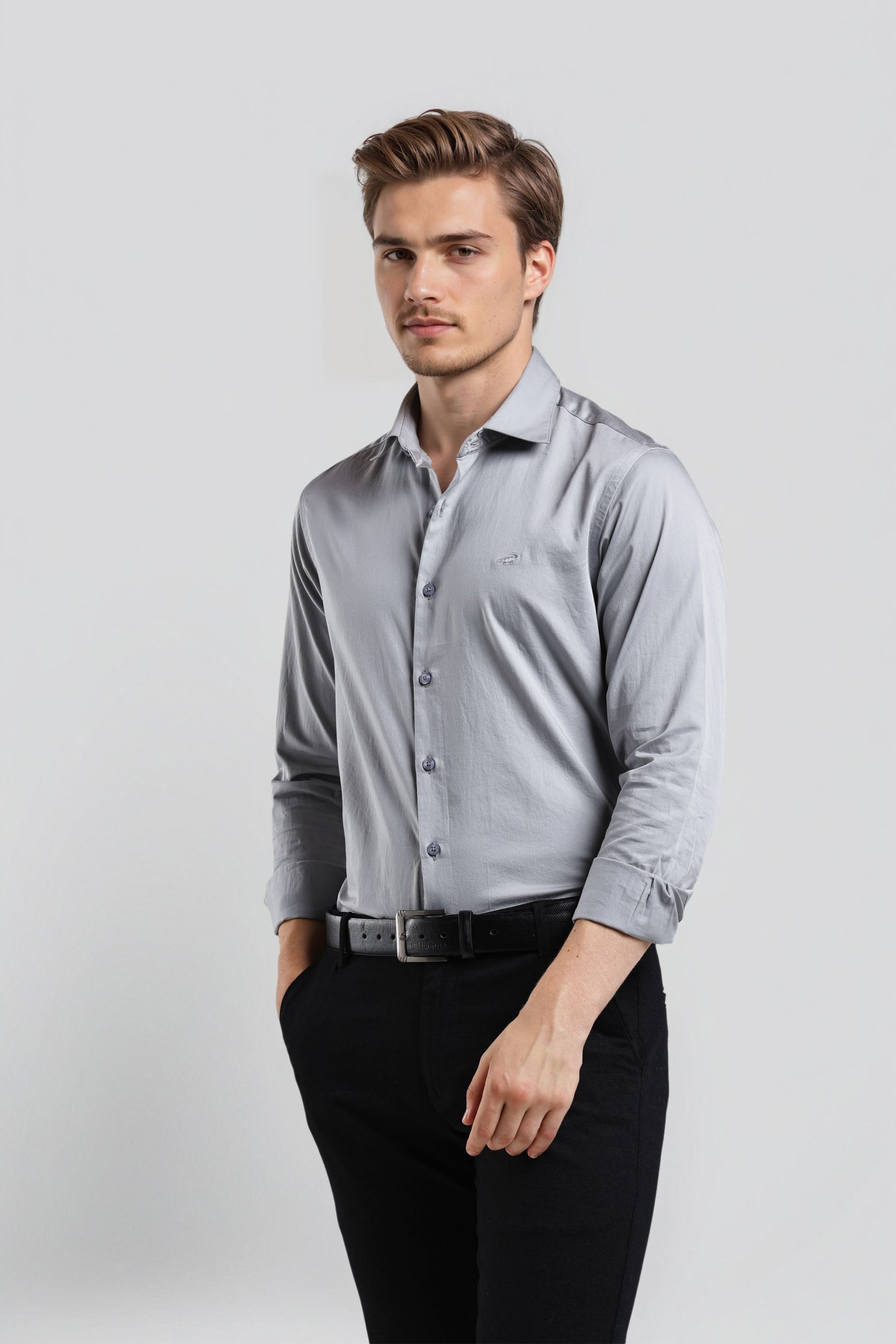 Man wearing a light gray dress shirt and black pants on a white background