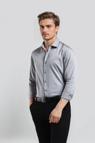 Man wearing a light gray dress shirt and black pants on a white background