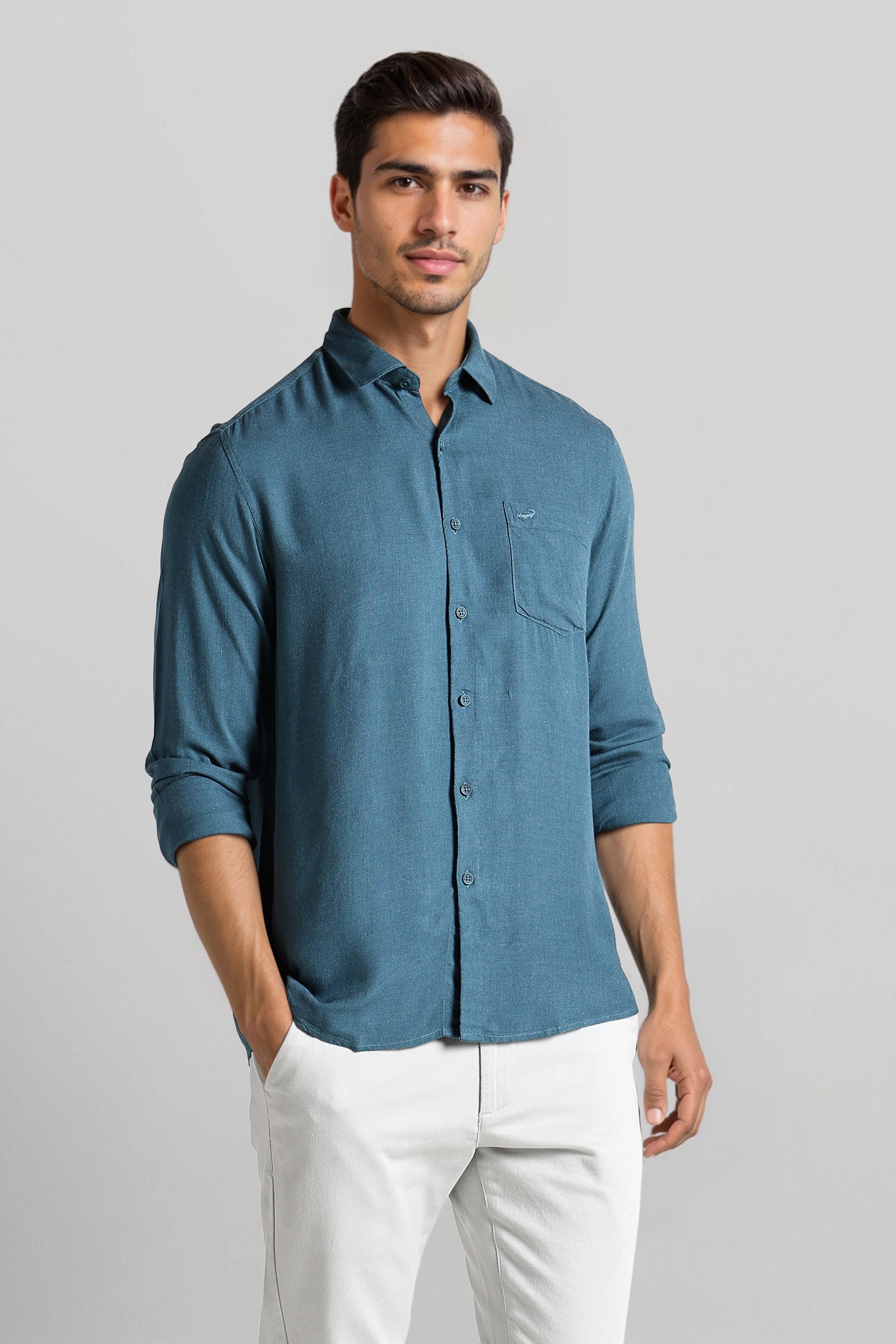 Man wearing a blue shirt and white pants on a gray background