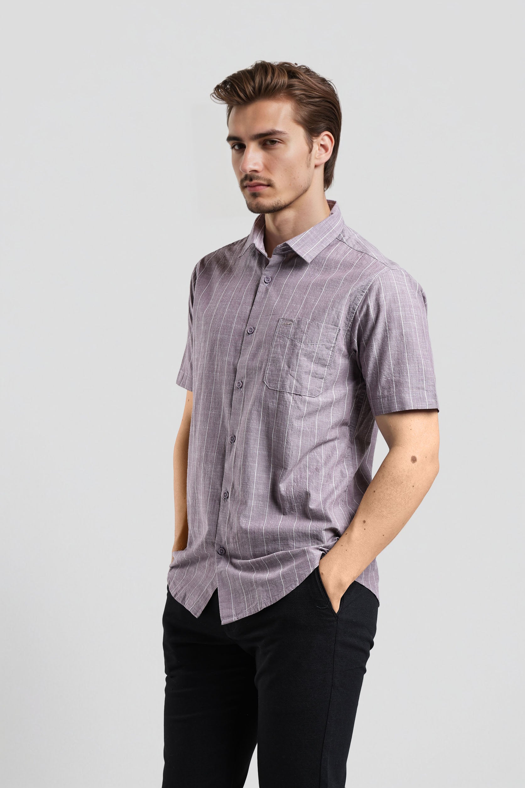 Man wearing a short-sleeve checkered shirt and black pants on a light gray background