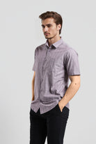 Man wearing a short-sleeve checkered shirt and black pants on a light gray background