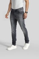 Person wearing gray jeans and white sneakers on a plain background