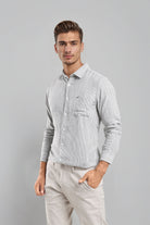 Man wearing a light gray checkered shirt and beige pants against a gray background