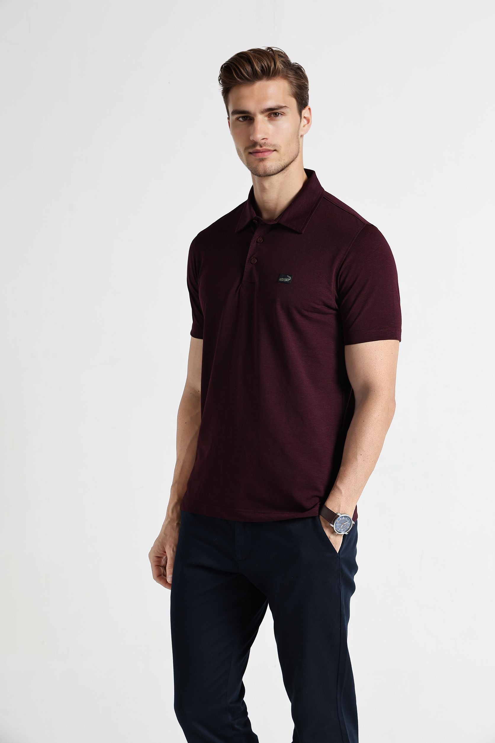 Man wearing a maroon polo shirt with a logo on a white background