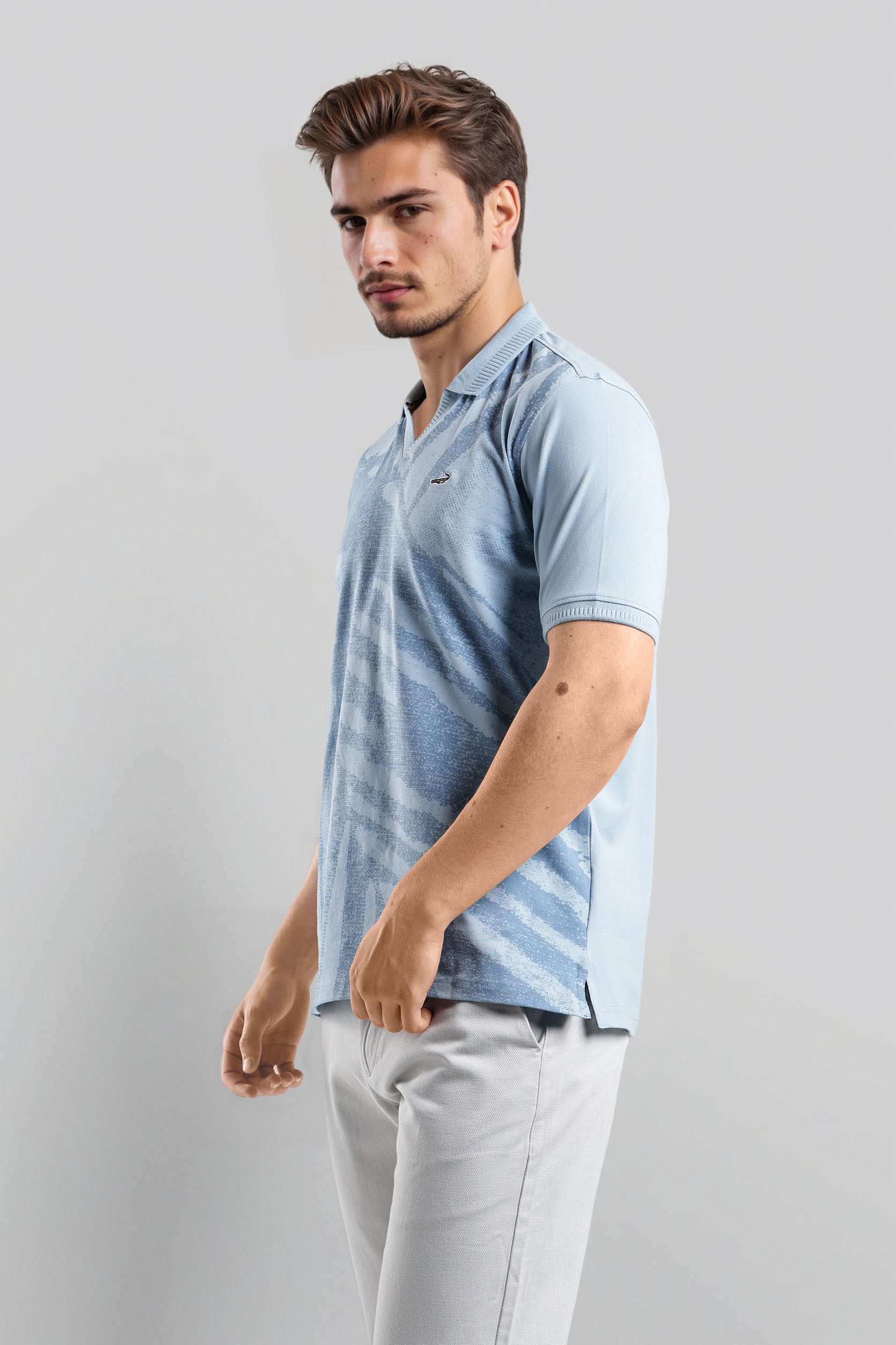 Man wearing a light blue striped polo shirt against a gray background