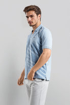 Man wearing a light blue striped polo shirt against a gray background