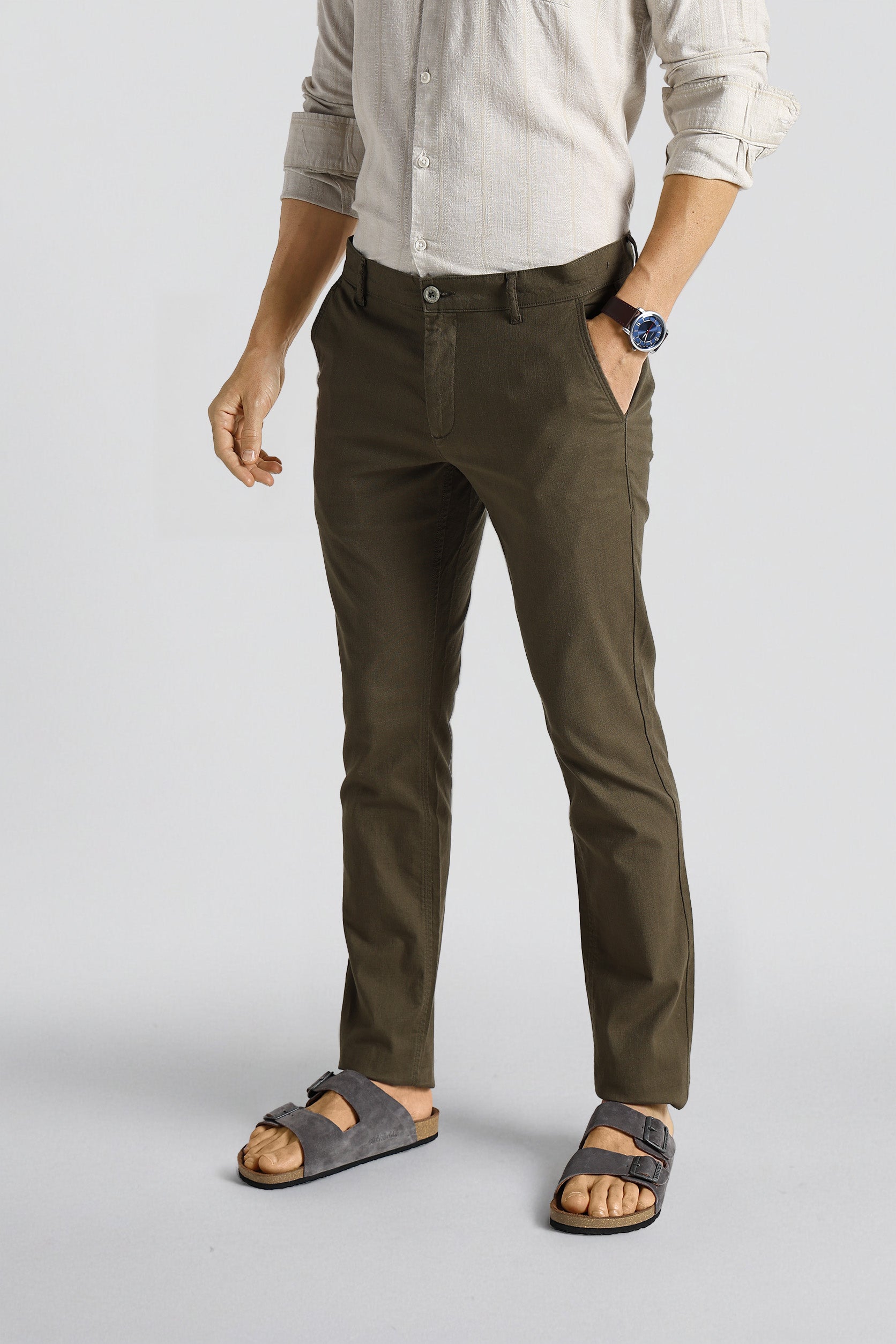 Person wearing olive green pants and sandals on a light gray background