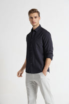 Man wearing a dark blue shirt and white pants on a white background