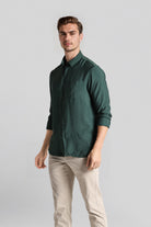 Man wearing a green shirt and beige pants on a gray background