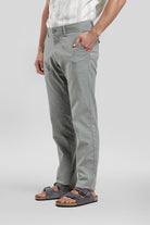 Person wearing gray pants and sandals on a plain background