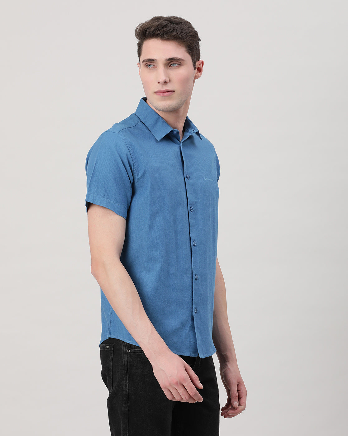 Man wearing a blue royal blue solid half sleeve linen shirt on a light gray background