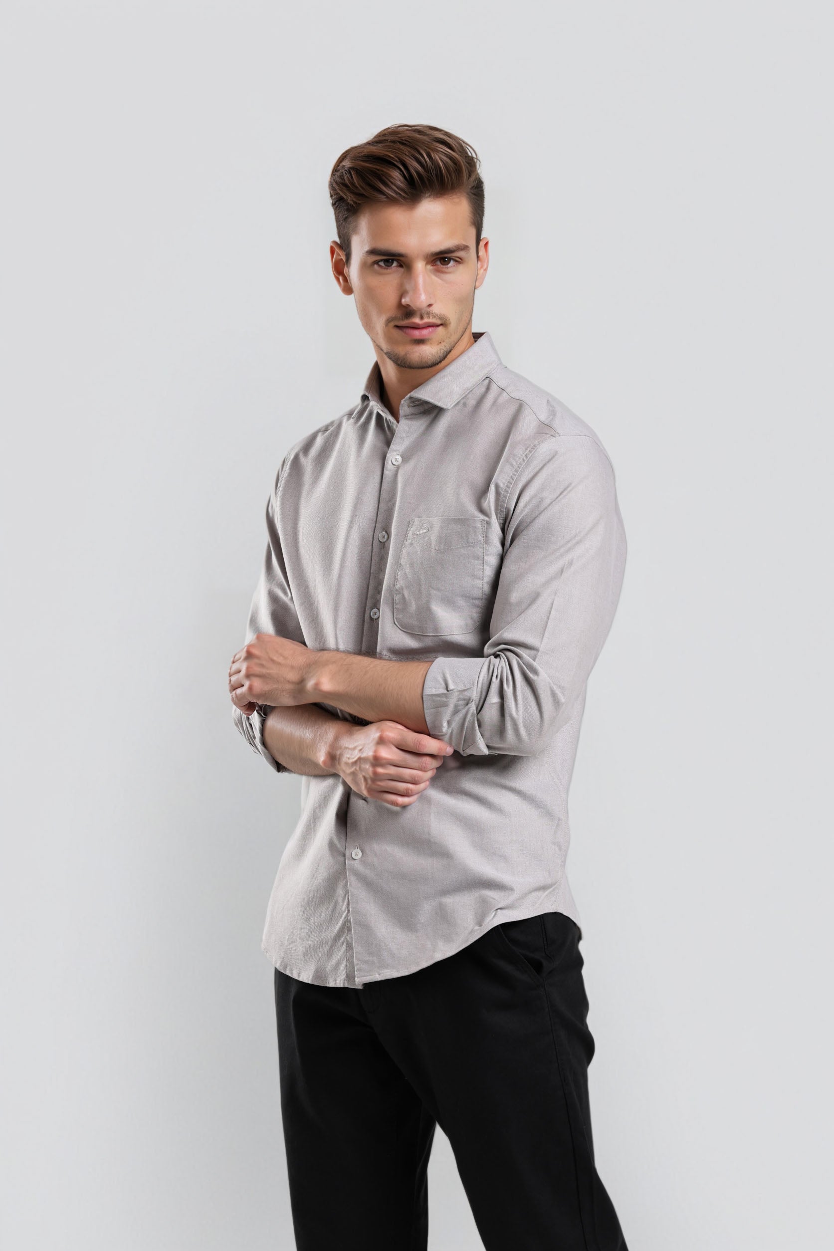 Man wearing a light gray button-up shirt and black pants on a white background