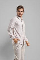 Man wearing a light pink shirt and beige pants against a gray background