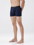 Person wearing navy blue boxer briefs with a visible brand logo on a white background