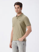 Man wearing a olive light olive structure comfort fit polo t shirt on a light gray background