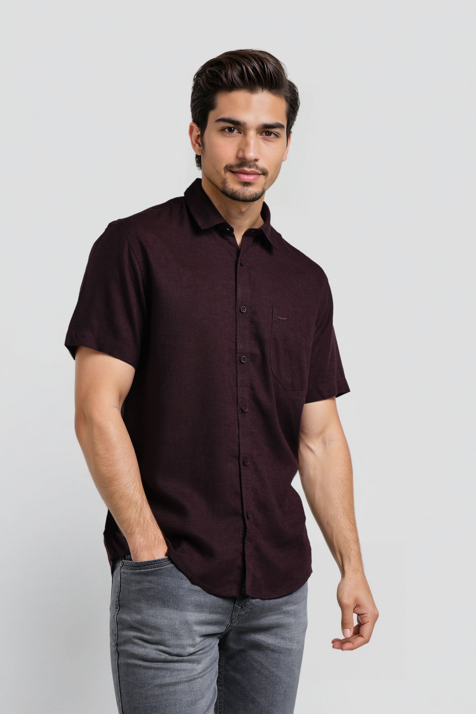 Man wearing a dark brown button-up shirt and gray pants on a white background