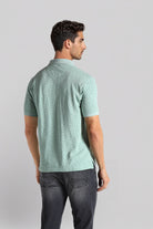 Man wearing a green patterned shirt on a light gray background