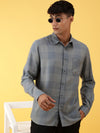 Man wearing a grey grey checked full sleeve shirt on a light gray background