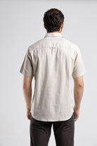 Man wearing a beige short-sleeve shirt on a white background