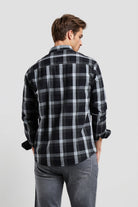 Man wearing a black and gray plaid shirt on a light gray background