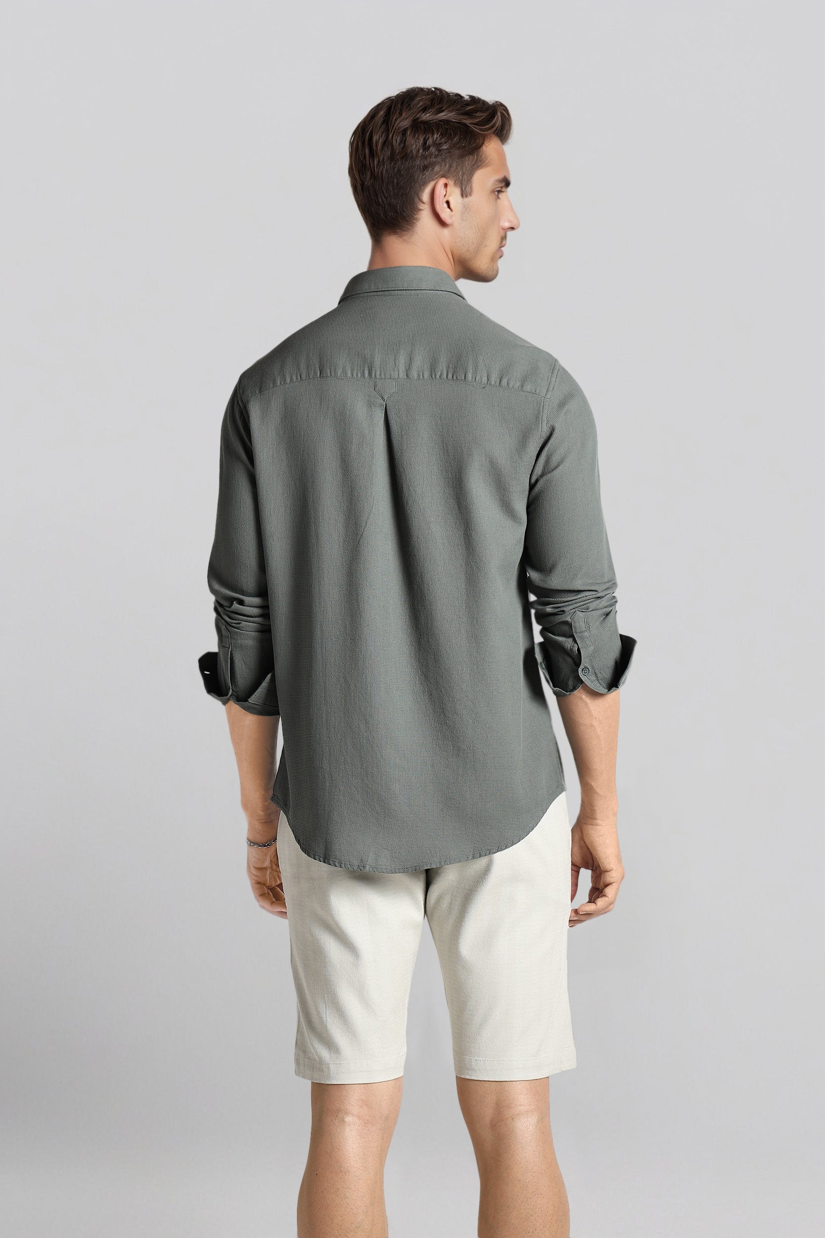 Man wearing a gray shirt and white shorts on a light gray background