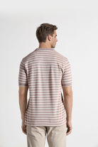 Man wearing a striped shirt and beige pants on a white background