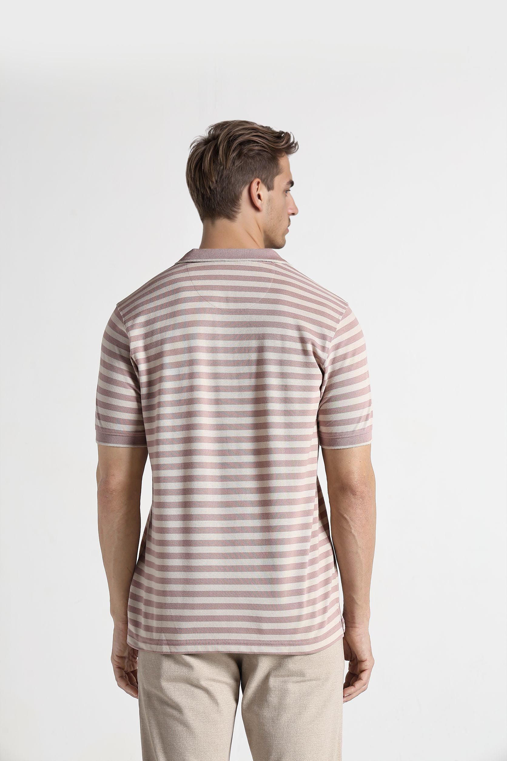 Man wearing a striped shirt and beige pants on a white background