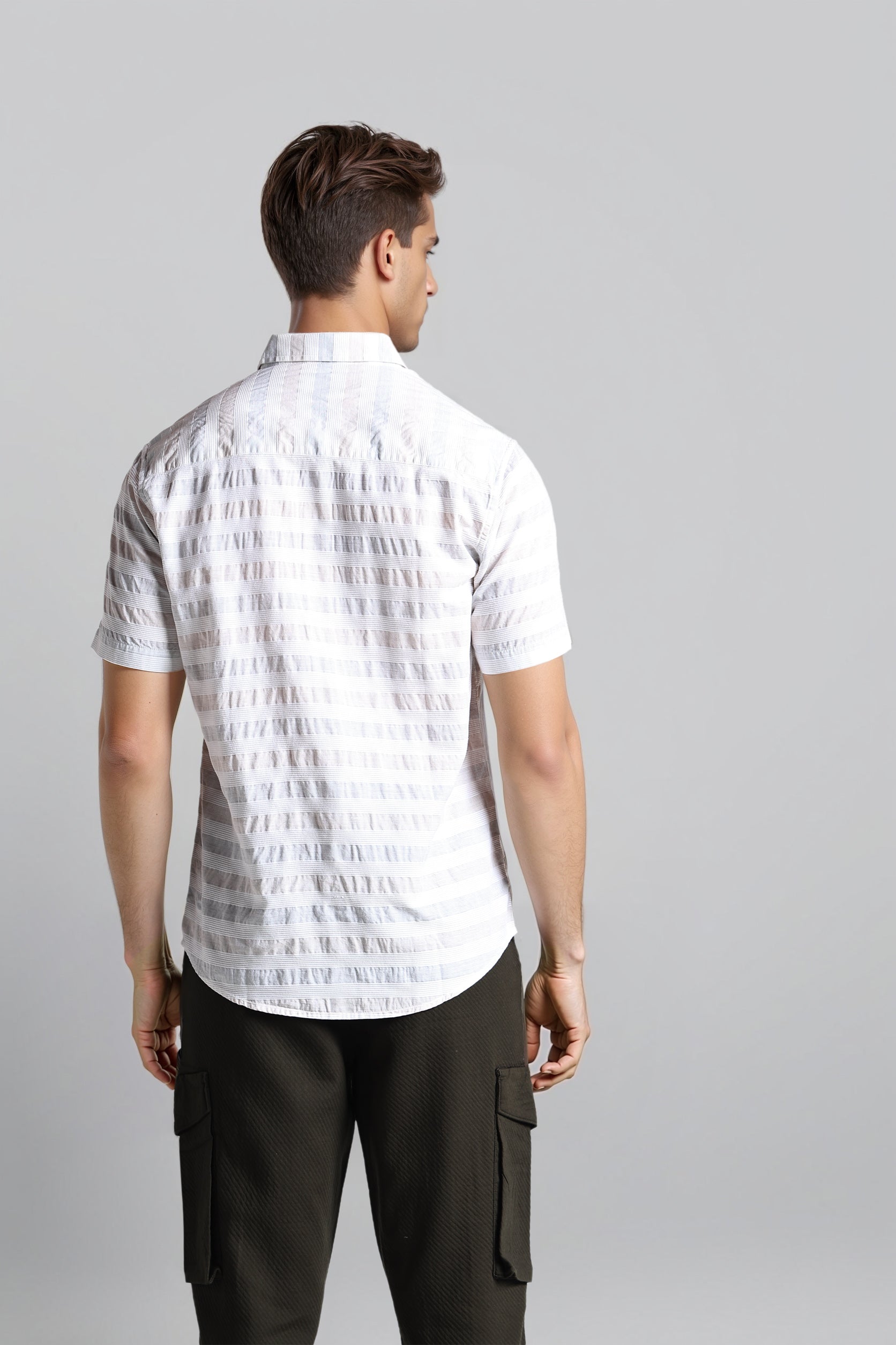 Man wearing a white patterned shirt and black pants on a gray background