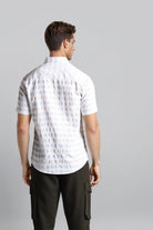 Man wearing a white patterned shirt and black pants on a gray background