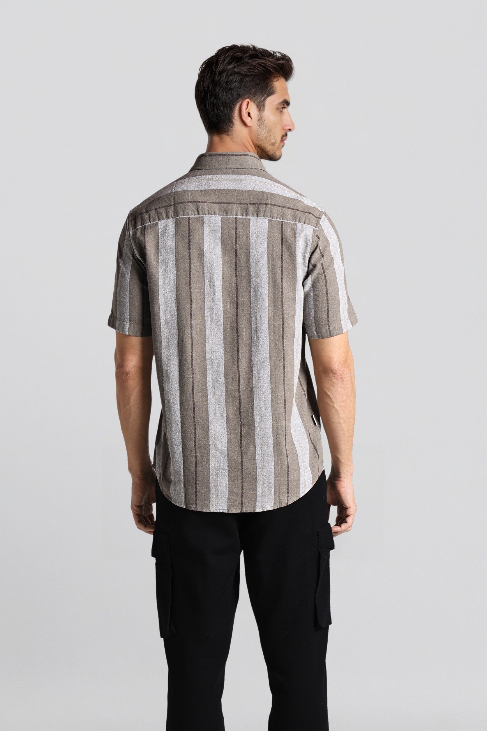 Man wearing a striped shirt and black pants on a light gray background