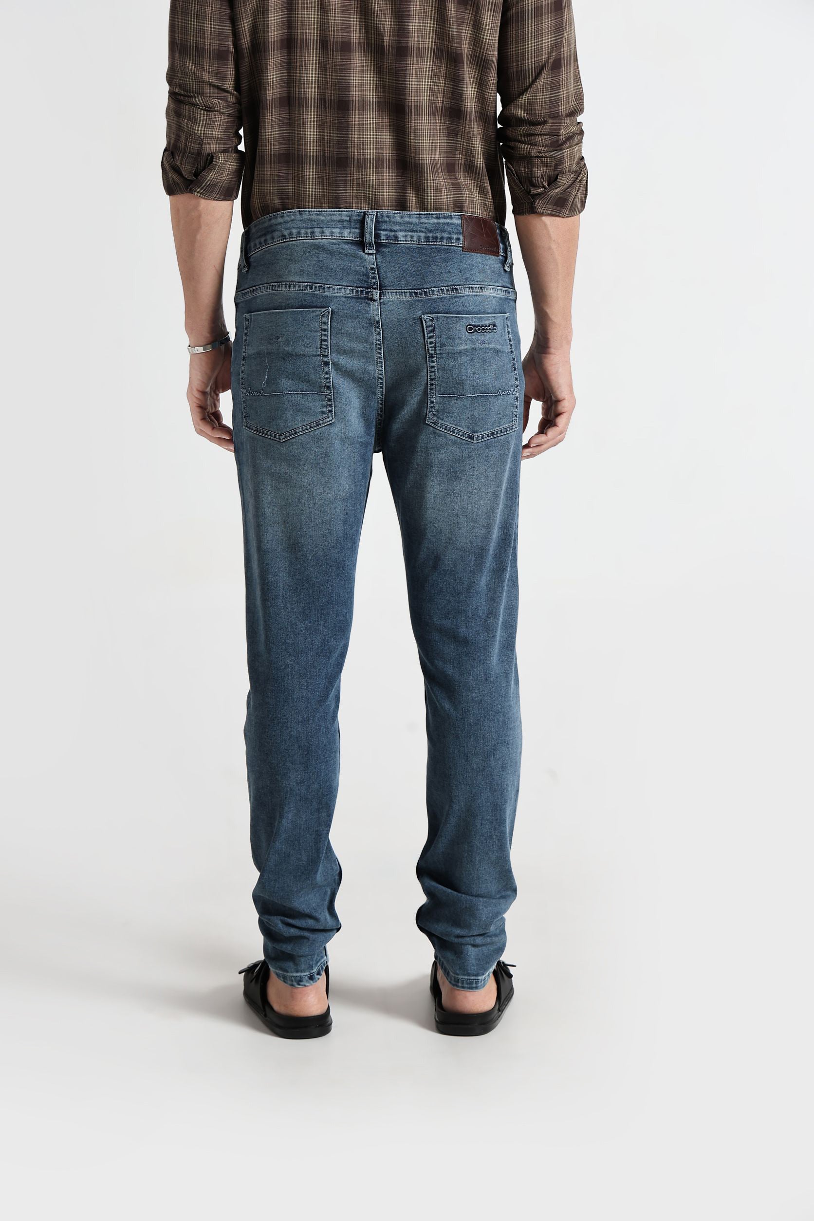 Person wearing blue jeans and a plaid shirt on a white background