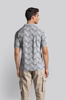 Man wearing a gray patterned polo shirt and beige cargo pants on a light gray background