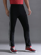 Person wearing black pants with white stripes and red sneakers on a gray background