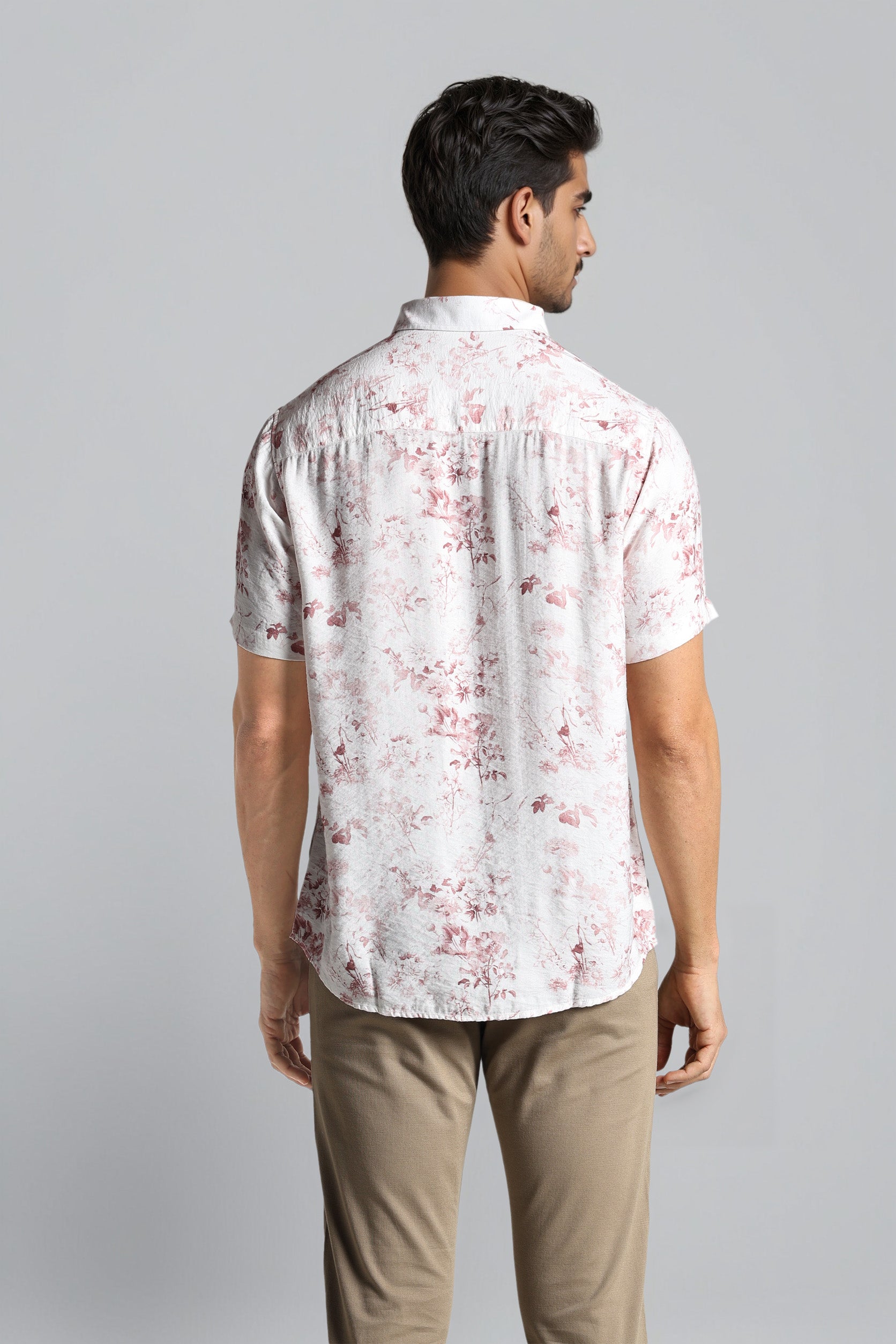 Man wearing a white floral patterned shirt against a gray background