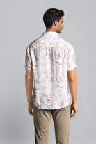 Man wearing a white floral patterned shirt against a gray background