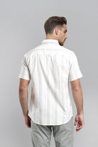 Man wearing a white short-sleeve shirt with subtle pattern on a gray background