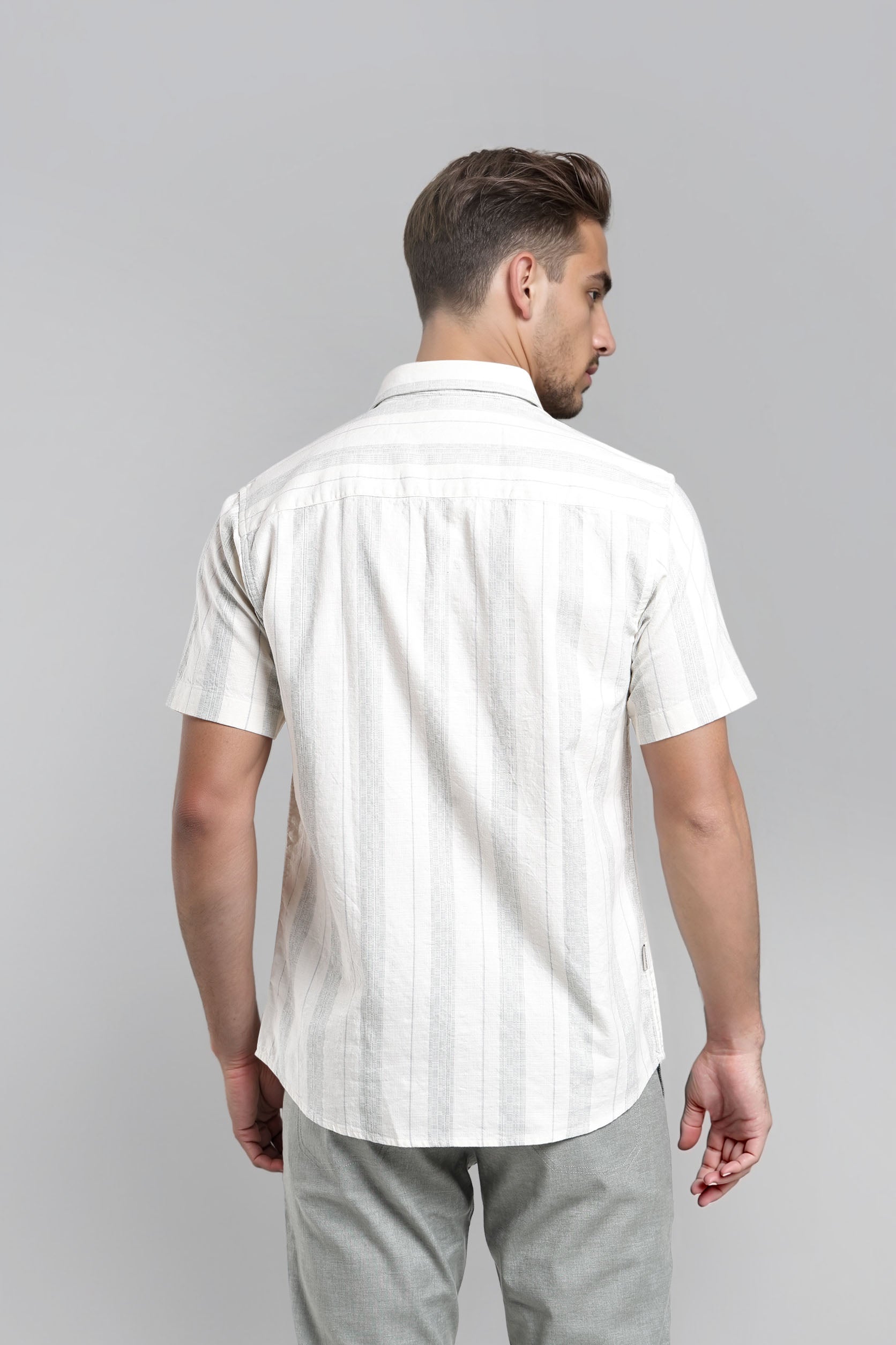 Man wearing a white short-sleeve shirt with subtle pattern on a gray background