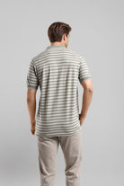 Man wearing a striped polo shirt and beige pants on a gray background