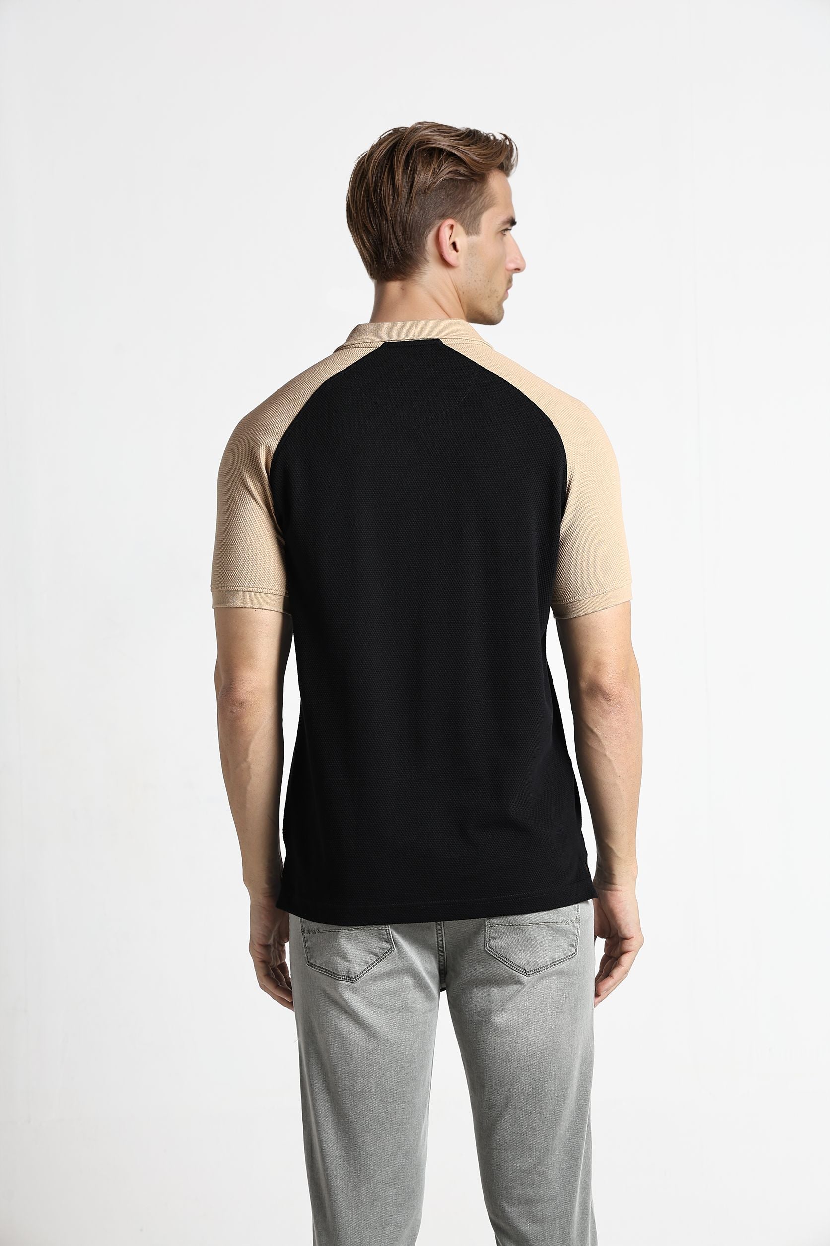 Man wearing a black and beige sleeveless shirt on a white background