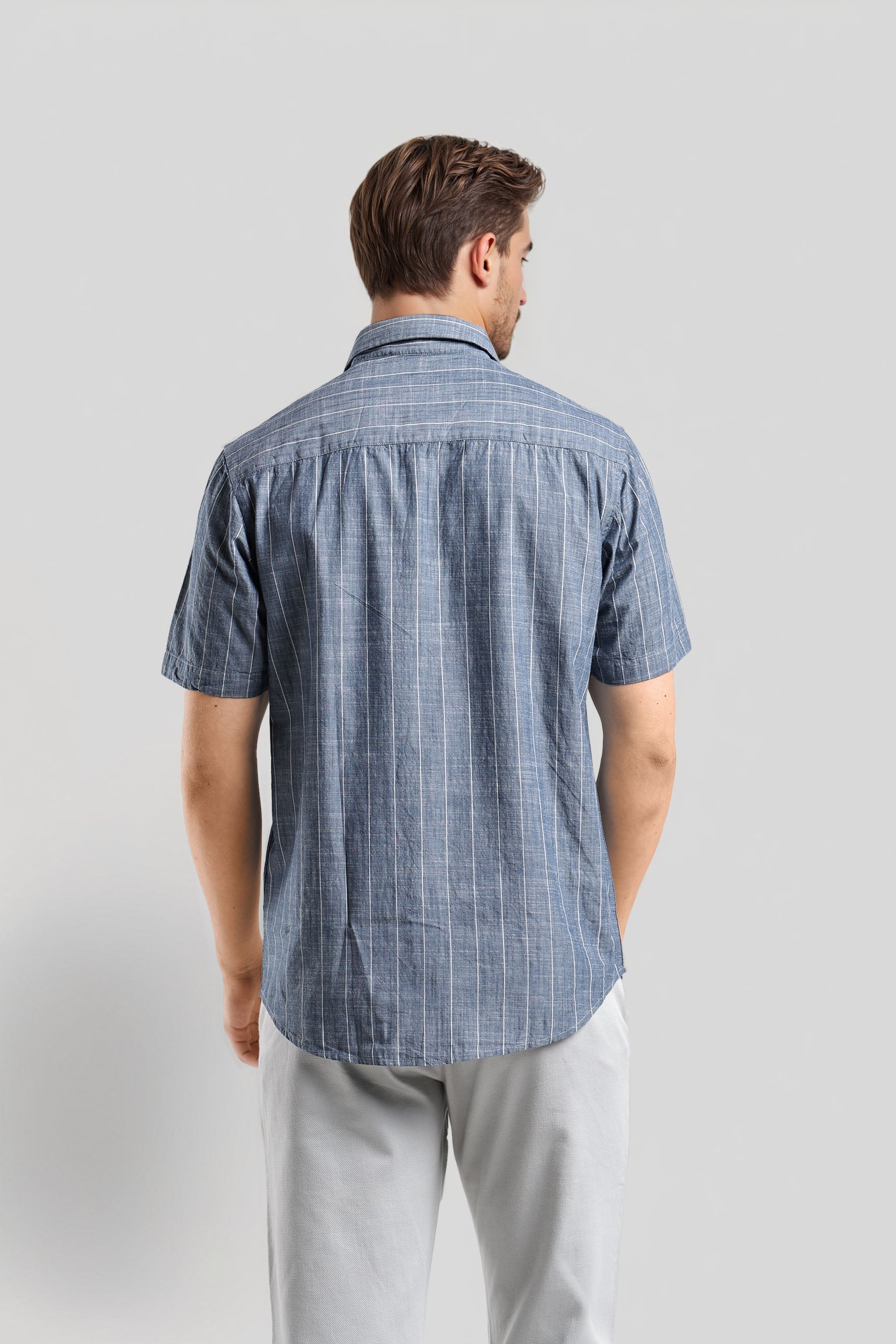Man wearing a blue checkered shirt against a gray background