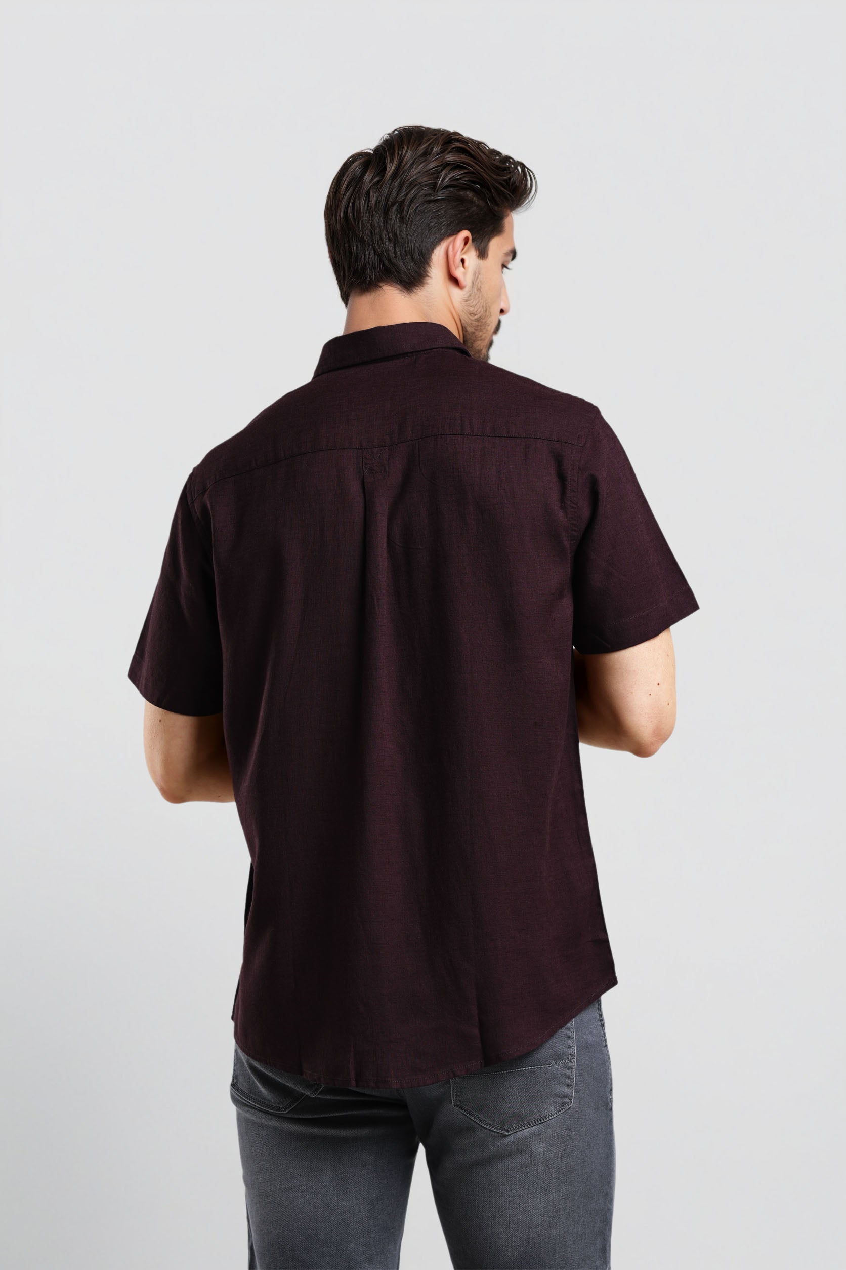 Man wearing a dark brown short-sleeve shirt on a light gray background