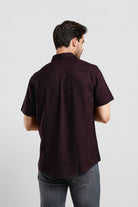 Man wearing a dark brown short-sleeve shirt on a light gray background