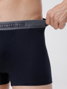 Person wearing black boxer briefs with a gray waistband, holding the waistband.