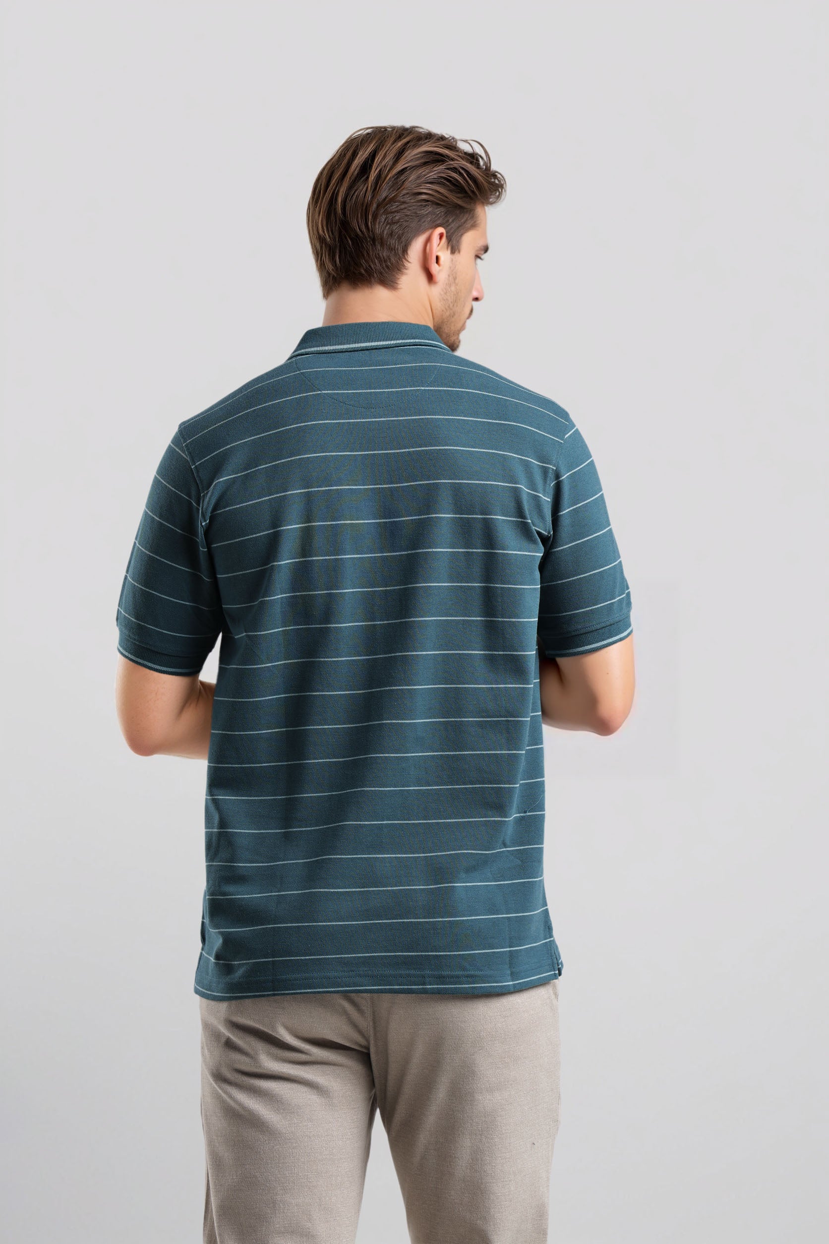 Man wearing a blue striped polo shirt against a light gray background