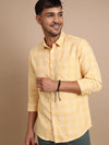 Man wearing a yellow casual yellow checked full sleeve 100% cotton shirt with casual styling on a gray background