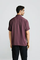 Man wearing a maroon shirt and black pants on a white background