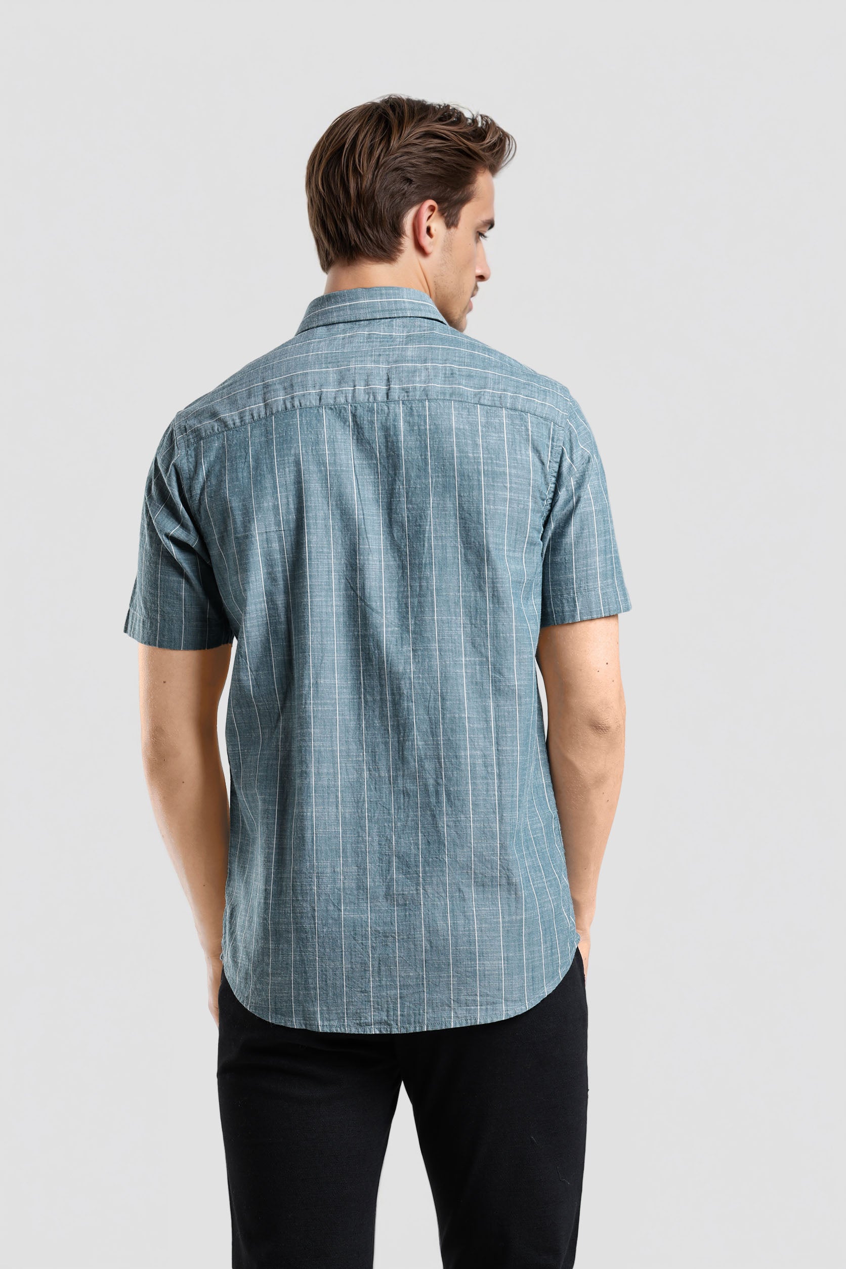 Man wearing a blue checkered shirt on a light gray background