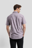 Man wearing a short-sleeve checkered shirt against a plain background