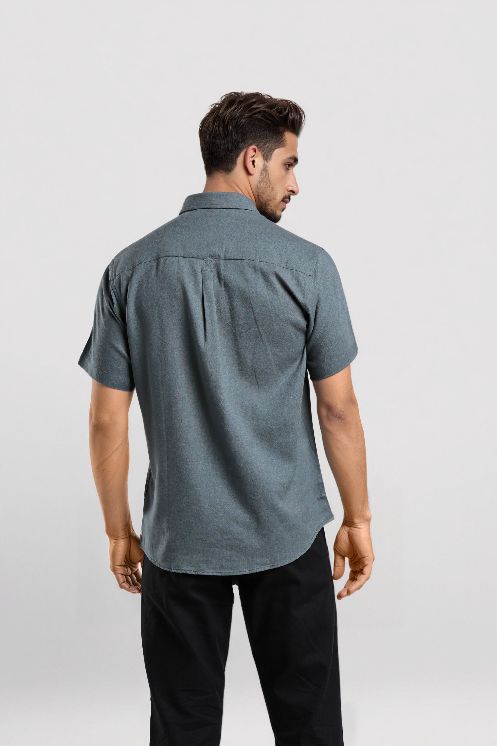 Man wearing a gray short-sleeve shirt and black pants on a white background